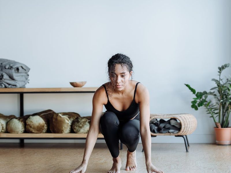 Person in a focused yoga pose in a minimalist setting.